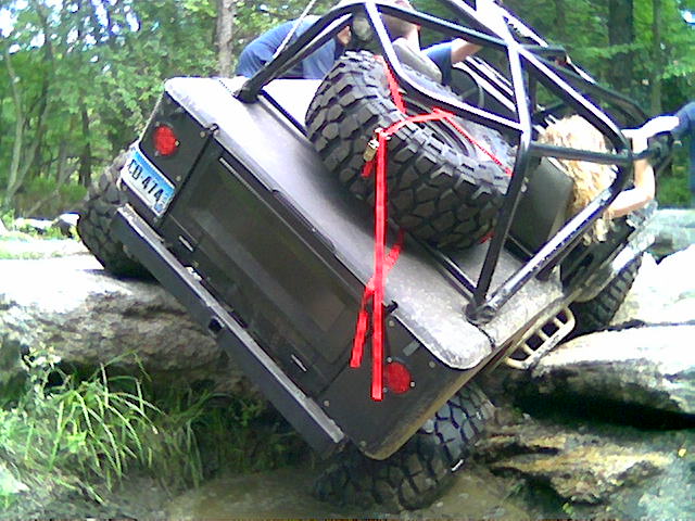 Off-road vehicle with roll cage and spare tire on rocks, license plate CD-414