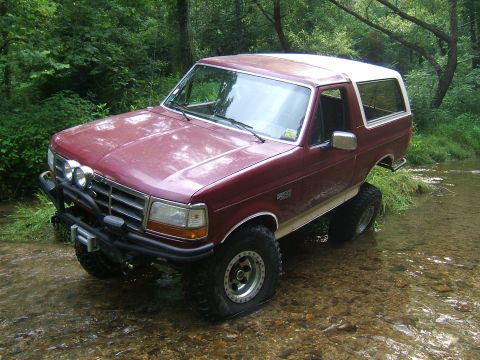 1993 Ford Bronco - 1993 Ford Bronco navigating a shallow stream in a wooded area.