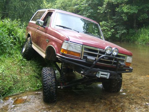 1993 Ford Bronco - This red 1993 Ford Bronco navigates a rocky stream bed, its off-road capabilities.