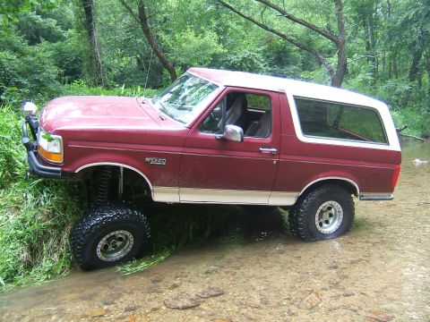 1993 Ford Bronco - This Ford Bronco is partially submerged in a stream, with its front tires on the grassy bank.