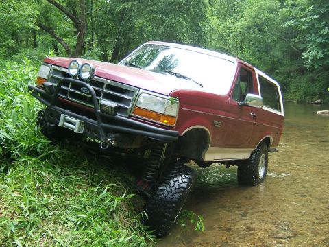 1993 Ford Bronco - Red 1993 Ford Bronco navigating a stream, showing off its off-road capabilities.