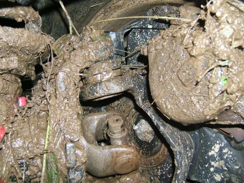 1993 Ford Bronco - Close-up view of heavily mud-caked suspension components on a vehicle.