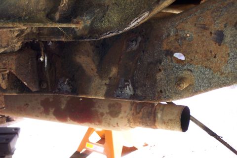 1978 Ford Bronco - Close-up view of heavily rusted vehicle undercarriage components, including the frame and exhaust system.