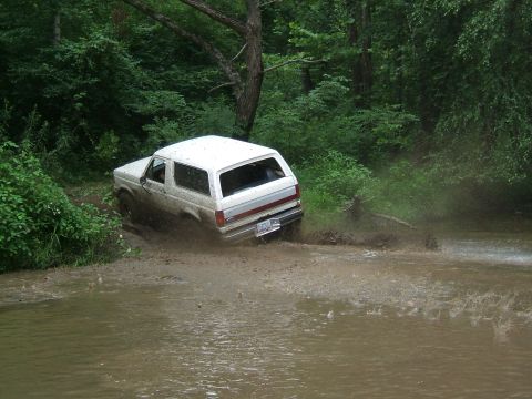 1993 Ford Bronco - White 1993 Ford Bronco navigating a muddy off-road path.