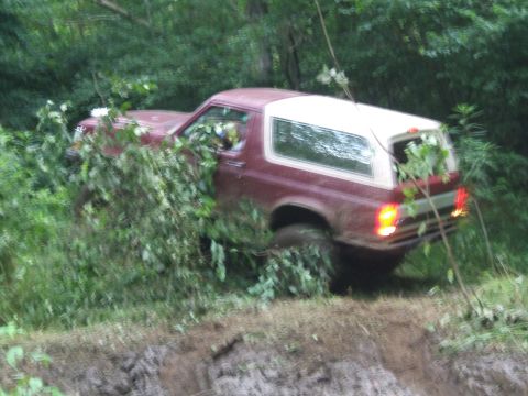 1993 Ford Bronco - 1993 Ford Bronco navigating a muddy, overgrown trail.