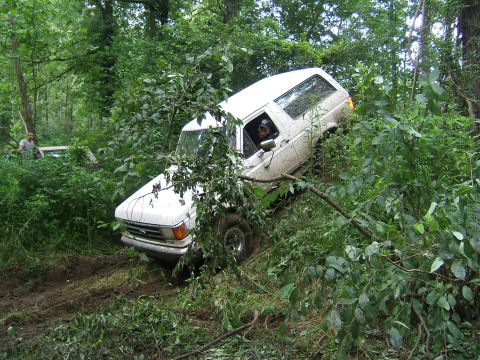 1993 Ford Bronco - A white SUV is stuck in the mud off-road, with another vehicle visible in the background.