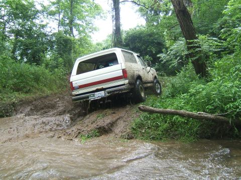 1993 Ford Bronco - This 1993 Ford Bronco navigates a challenging muddy terrain, with its tires kicking up dirt and water.