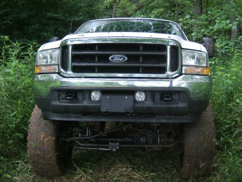 1993 Ford Bronco - This lifted Ford truck sits high on muddy tires, ready for off-road adventure in a natural setting.