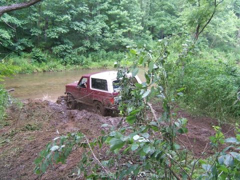 1993 Ford Bronco - 1993 Ford Bronco navigating a muddy trail and creek crossing.