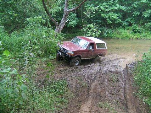 1993 Ford Bronco - This 1993 Ford Bronco navigates a muddy off-road trail near a stream.