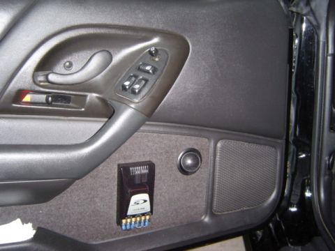 2002 Chevrolet Camaro - Interior view of a car door panel showing the door handle, window controls, and an aftermarket audio amplifier.