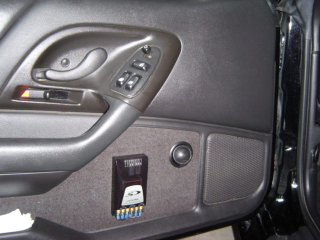 Car door panel with power window controls, speaker, and aftermarket Alpine amplifier