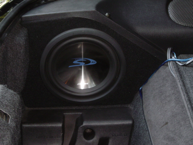 Alpine subwoofer mounted in a black custom enclosure in a car's trunk