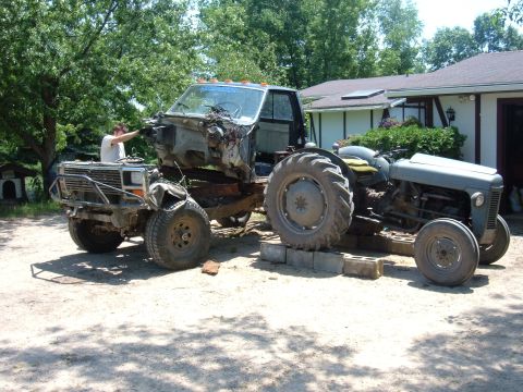 1985 Ford F-150 - A truck chassis is being worked on, connected to a tractor in a yard.
