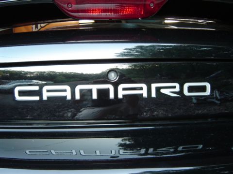 2002 Chevrolet Camaro - Rear view of a black Chevrolet Camaro, showing the CAMARO emblem and a reflection of the same emblem.