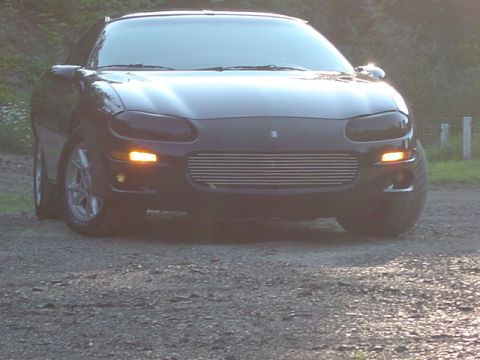 2002 Chevrolet Camaro - Front view of a black Chevrolet Camaro with tinted headlights and an aftermarket grille.