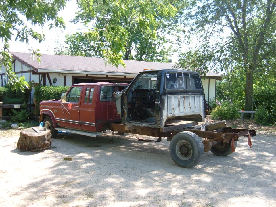 Red crew cab truck body on a bare frame with a black cab attached behind it