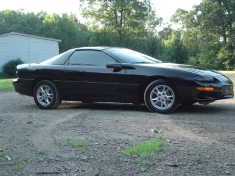 2002 Chevrolet Camaro - A black 2002 Chevrolet Camaro is shown from the front three-quarter angle on a gravel surface with trees in the background.