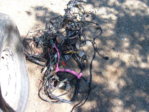 1985 Ford F-150 - Vehicle wiring harness spread out on the ground, partially obscured by a tire.
