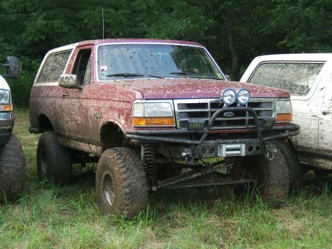 1993 Ford Bronco - Mud-covered 1993 Ford Bronco with off-road modifications parked next to another vehicle.