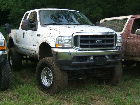 1993 Ford Bronco - Muddy Ford F-Series truck with lifted suspension and aftermarket wheels.