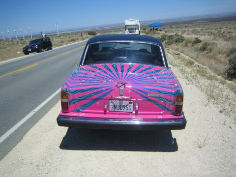 1968 Ford Mustang - A brightly decorated Rolls-Royce sits on the side of a road with a black SUV and RV in the distance.