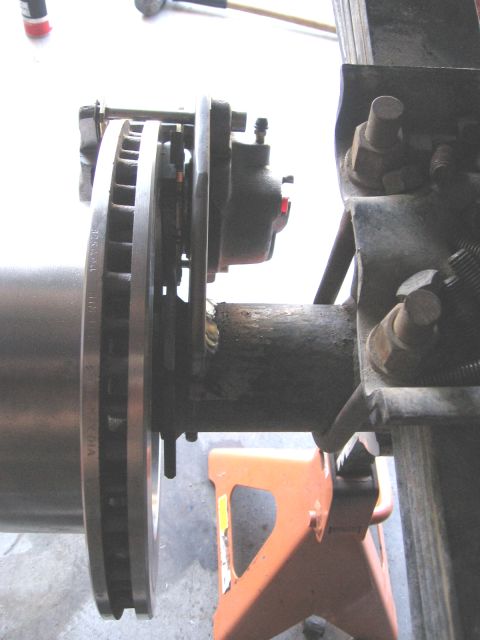 1994 Ford Bronco - Close-up view of a vehicle's disc brake assembly and axle, resting on an orange jack stand.