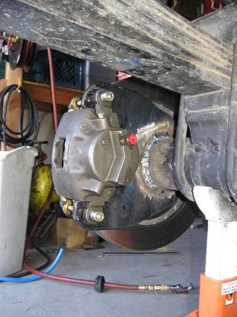 1994 Ford Bronco - Close-up of a vehicle's rear disc brake assembly, showing the caliper and rotor.