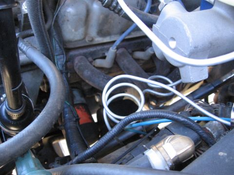 1994 Ford Bronco - A detailed view of an engine bay, focusing on the spark plug wires and exhaust manifold with surrounding components.