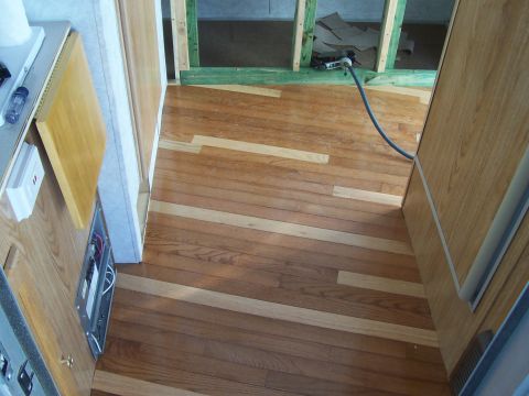1994 Ford F-150 - The interior of a vehicle shows hardwood flooring and exposed framing, indicating ongoing construction or renovation work.