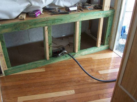 1994 Ford F-150 - The interior of a camper shows unfinished wooden framing and a black power cord running across the floor.