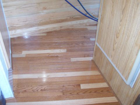 1994 Ford F-150 - The interior of a camper shows a wooden floor with a visible water stain and some blue cables overhead.