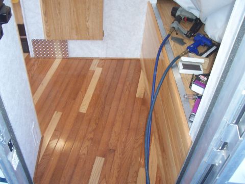 1994 Ford F-150 - Tools, including nail guns and hoses, are laid out on the floor and counter of a camper's interior, which features wood paneling and floori…