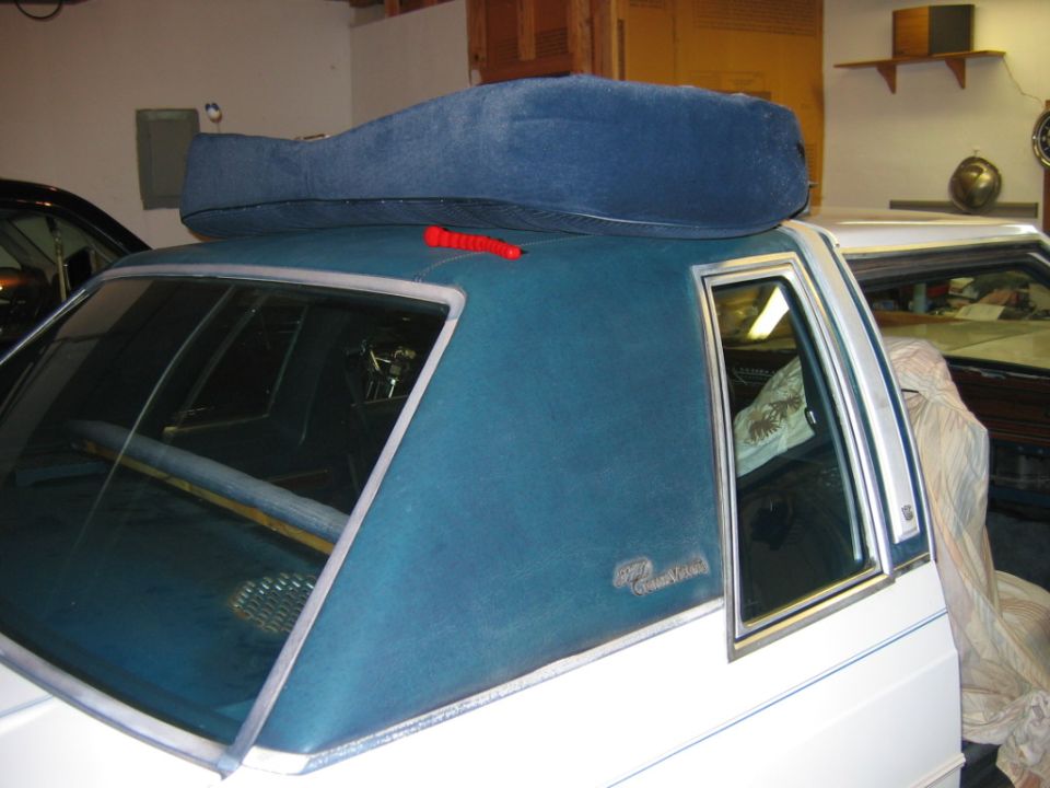 car roof with blue cushion and red emergency flasher on top, another car visible behind it