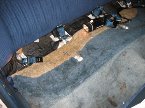 1985 Ford LTD Crown Victoria - The interior of a 1985 Ford Crown Victoria LTD shows worn blue carpeting and visible seatbelt mechanisms.