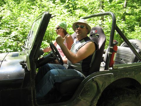 1977 Ford F-150 - Two individuals enjoy a ride in a Jeep CJ through a wooded trail, with a fire extinguisher visible inside the vehicle.