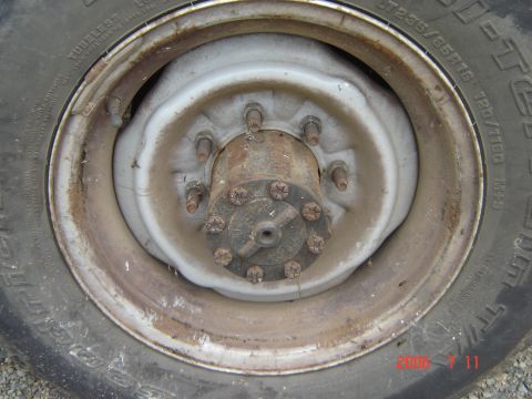 1993 Ford Bronco - Close-up of a rusty wheel hub and tire, showing lug nuts and tire size information.
