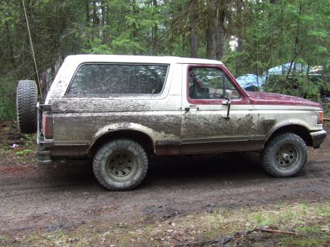 1990 Ford Bronco - This 1990 Ford Bronco is heavily covered in mud, suggesting off-road use.