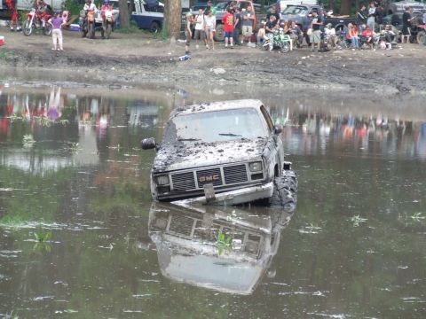 1990 Ford Bronco - GMC pickup truck submerged in mud, stuck during an event. Appears to be a 1988 model.