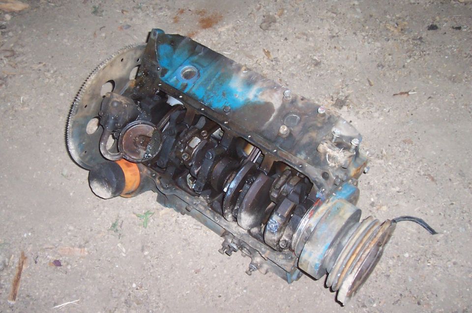 Engine block with crankshaft, oil filter, and pulley system visible. The engine is blue and appears to be disassembled