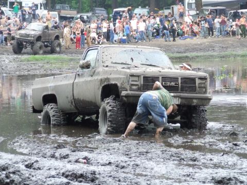 1990 Ford Bronco - A crowd watches as a GMC truck gets stuck in the mud during an off-road event.