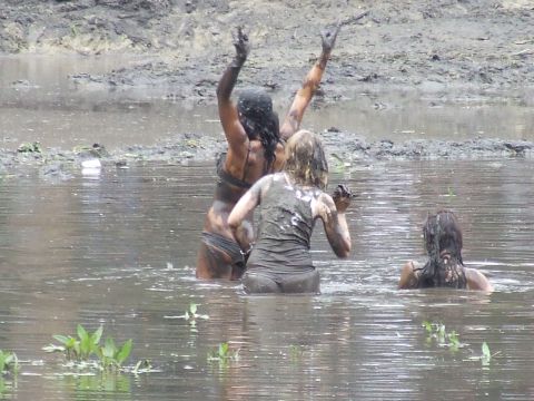 1990 Ford Bronco - Three people are enjoying themselves in a muddy waterhole, covered head to toe in mud.