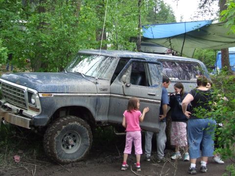 1990 Ford Bronco - Muddy 1979 Ford F-Series truck with people gathered around it in a wooded area.