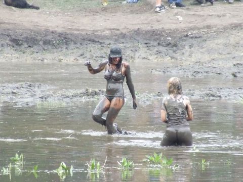1990 Ford Bronco - People play in the mud at an outdoor event.