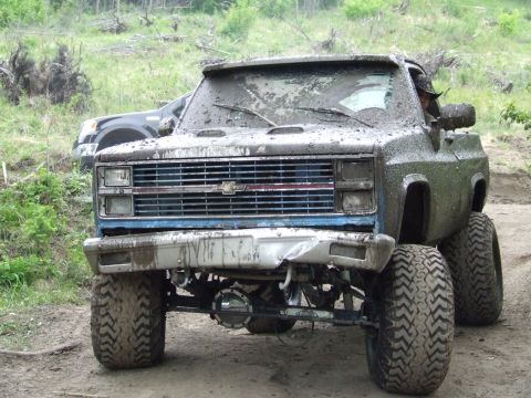 1990 Ford Bronco - Muddy lifted 1981 Chevrolet pickup truck with another vehicle in the background.