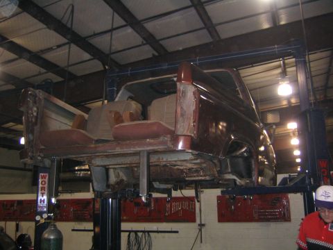 1982 Ford Bronco - The body of a maroon 1982 Ford Bronco is elevated on a lift in a workshop.