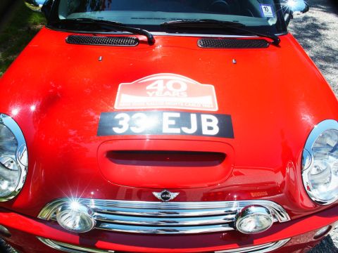 2001 Mercury Grand Marquis - Front view of a red Mini Cooper with rally decals and a license plate.