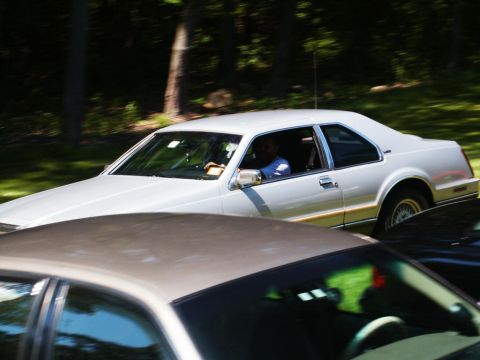 2001 Mercury Grand Marquis - A white coupe drives past, partially obscured by another vehicle in the foreground.