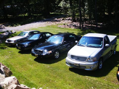 2001 Mercury Grand Marquis - Multiple vehicles are parked on a lawn during what appears to be an outdoor gathering.