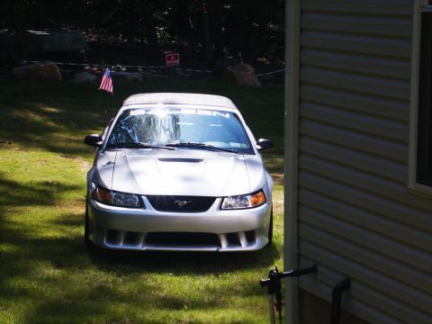 2001 Mercury Grand Marquis - Front view of a silver Ford Mustang parked on a lawn with a house to the right.